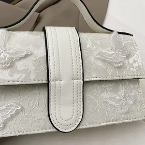 Detail of floral jacquard fabric and 3D white butterfly embroidery on square handbag