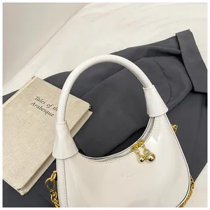 Detail of white hobo bag with glossy finish, gold sphere zipper and brand lettering