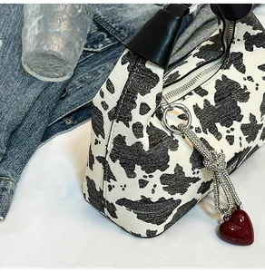 Detailed view of leopard print handbag featuring a red heart pendant and silver hardware