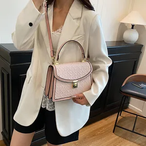 Dettaglio della texture con foglie rosa e chiusura a rotazione dorata sulla borsa