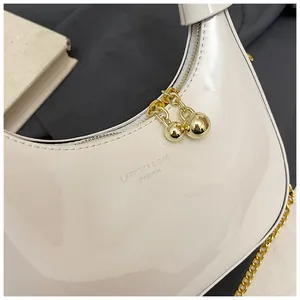 Macro detail of glossy cream crescent bag with golden ball zipper and embossed logo
