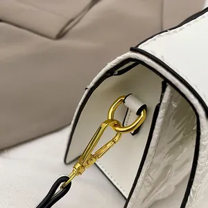 Macro shot of gold D-ring hardware and white textured jacquard fabric on stylish shoulder bag