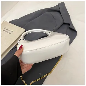 Detail of white glossy crescent handbag with golden chain strap and hobo design