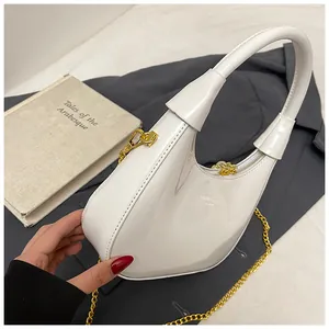 Detail of white crescent bag with shiny patent finish and gold metal chain strap