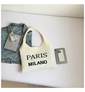 Platliggende weergave van crème gebreide draagtas met Paris Milano print en accessoires
