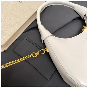 Detail of glossy white crescent bag featuring golden chain and polished patent leather