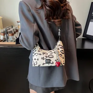 Detail of leopard print crossbody bag with red heart charm and brand leather label