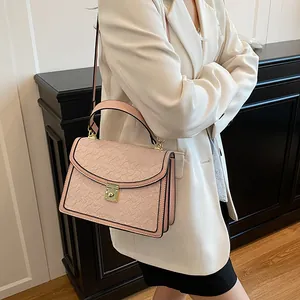 Dettaglio della borsa rosa con trama a rilievo e chiusura a girello oro su modella