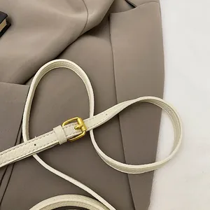 Détail de la bandoulière en cuir grainé crème avec boucle en métal doré et texture riche
