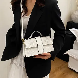 Detailed look at the white crossbody bag featuring delicate butterfly embroidery and a top handle