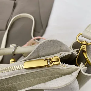 Détail de la texture grainée et de la fermeture éclair dorée sur le sac seau beige