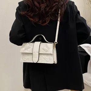 Detail of white square crossbody bag with 3D butterfly embroidery on black blazer