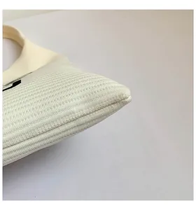 Detailopname van beige gebreide tas met focus op de textuur en de stevige afwerking
