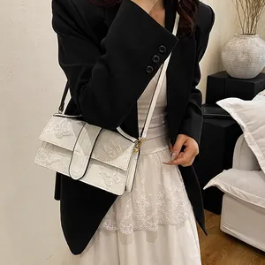 Detail of white leather shoulder bag featuring intricate 3D butterfly embroidery motifs
