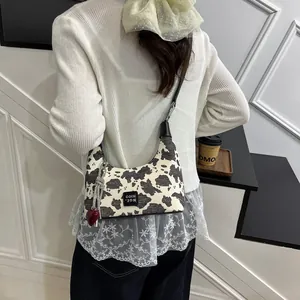 Detail of cow print crossbody bag with red heart charm and silver chain strap