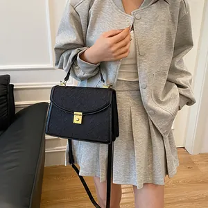 Modella che indossa una borsa nera a tracolla plissettata con fibbia dorata in interni