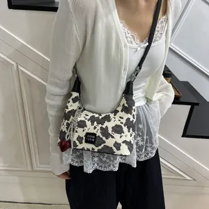 Detail of cow print crossbody bag with red heart pendant and long shiny tassels