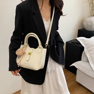 Détail du sac seau crème texture litchi avec fermoir doré et breloque ourson