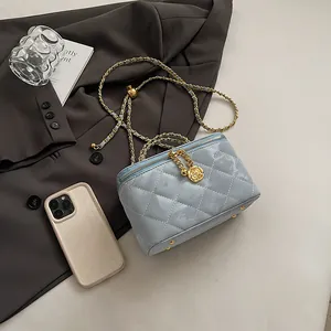 Détail du sac de maquillage en cuir verni bleu clair matelassé avec pendentif doré