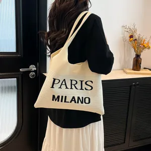 Detailopname van de gebreide shopper met PARIS MILANO-letters en zachte ribbeltextuur