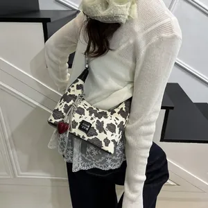 Detail of cow print shoulder bag with red heart charm and metallic chain accent