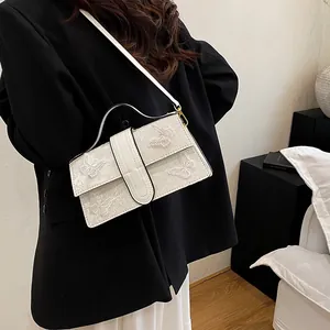 Detail of white butterfly embroidery on ivory structured handbag with top handle and strap