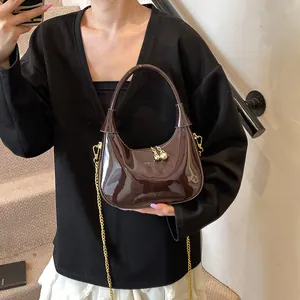Detail of glossy crescent bag in dark brown patent leather with gold chain and zipper