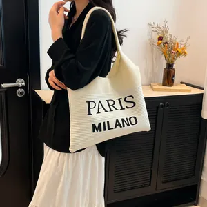 Detail van de textuur van beige gebreide draagtas met zwarte Paris Milano belettering
