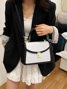 Elegante borsa a tracolla bianca e nera con trama jacquard e chiusura dorata su modella