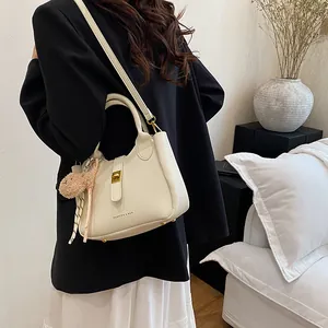 Détail du sac seau en cuir grainé blanc crème avec un charmant pendentif ours