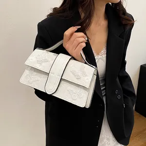 Detailed view of white handbag featuring elegant butterfly embossed texture and sturdy handle