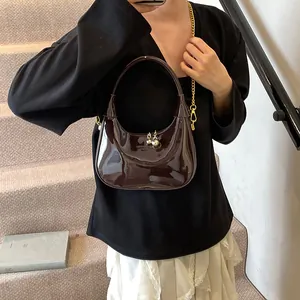 Deep brown patent leather half-moon bag with gold chain strap and metallic ball charms