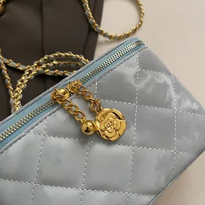 Détail du sac matelassé bleu clair avec breloque camélia dorée et chaîne à billes en métal