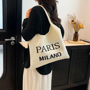 Witte gebreide shopper met Paris Milano opdruk op een donkere houten stoel