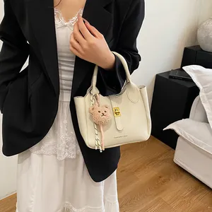Détail du sac seau crème avec texture lychee, pendentif ours et fermoir en métal doré
