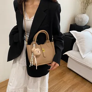 Détail d'un sac seau en cuir litchi kaki avec fermoir doré et breloque petit ourson