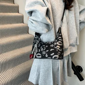 Close-up of black leopard print hobo bag with red heart pendant and metallic buckle