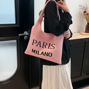 Detail van roze gebreide draagtas met zwarte Paris Milano-belettering en zachte textuur