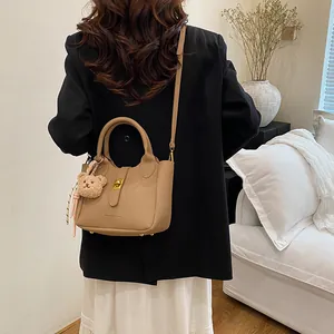 Détail du sac seau en cuir grainé kaki avec fermoir doré et breloque ours sur le modèle