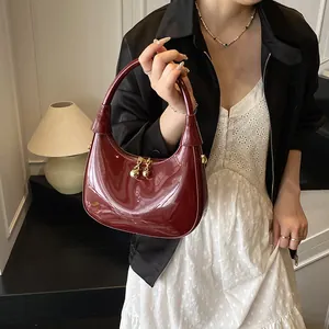 Detail of burgundy crescent hobo bag featuring glossy finish and gold ball zipper pull