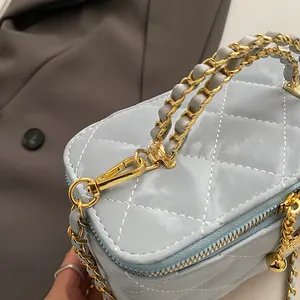 Détail du sac de maquillage bleu clair matelassé avec chaîne dorée et breloque boule