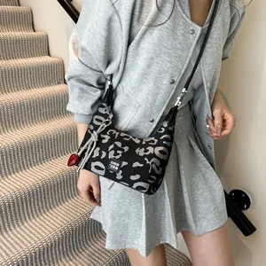 Detail of black canvas crossbody bag with silver patterns and red heart pendant charm