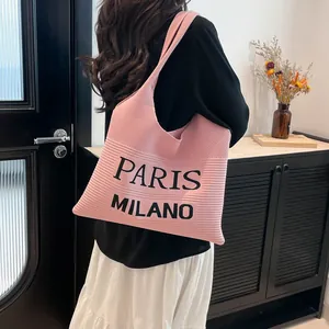 Detail van roze gebreide draagtas met zwarte Paris Milano belettering en textuur