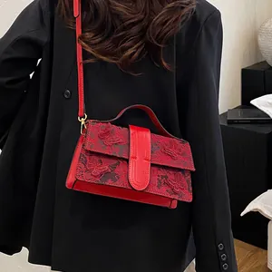 Detail of red crossbody bag with 3D butterfly floral embroidery and golden metal hardware
