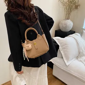 Détail du sac seau en cuir grainé kaki avec fermoir doré et accessoire d'ours en peluche