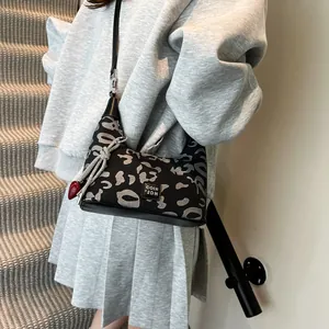 Detail of crossbody leopard print bag with red heart pendant and silver knot charm