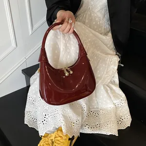 Deep red crescent handbag with high-gloss finish and gold ball-shaped zipper detail
