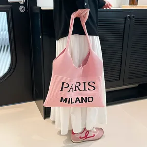 Detail van roze gebreide draagtas met Paris Milano tekst en geweven textuurpatroon