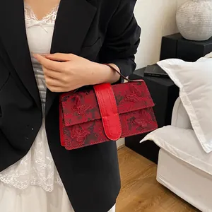 Detail of red fabric lace handbag featuring elegant 3D butterfly embroidery and leather strap