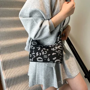 Close-up of leopard print canvas shoulder bag with branded square patch on a staircase